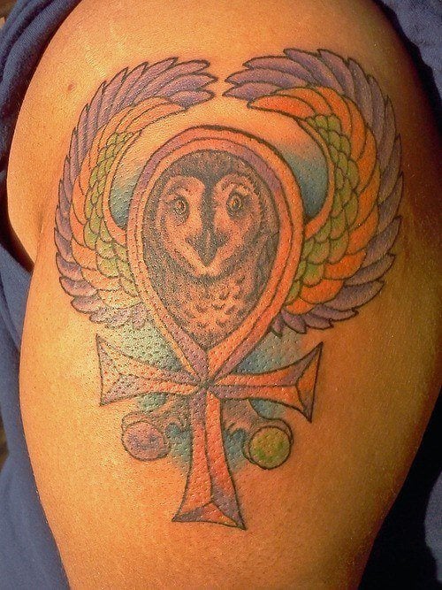 A color tattoo of an ankh or key of life symbol with a flying owl