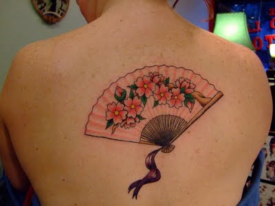Feminine upper back tattoo of a geisha’s fan. The flowers and the fan