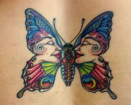 A hippy butterfly tattoo that has womens faces in the patterns on the wings