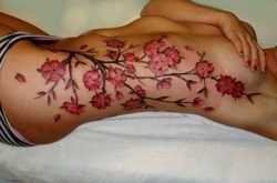 An elegant and feminine cherry blossom tattoo design on a girls side