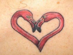 A sweet heart tattoo made up of two flamingo heads in a romantic pose