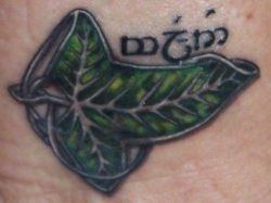 A Lord of the Rings tattoo of a leaf of Lorien brooch with Tengwar script that reads FRIEND