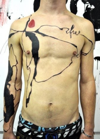An abstract tattoo by tattoo artist Musa that looks as though someone has spilled ink all over this guy