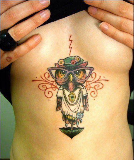 A cute and creative tattoo of an owl with glasses and flowers on its hat