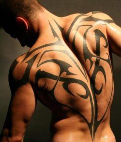 A sexy athletic guy shows off a tribal tattoo design that shows off his muscles