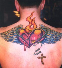 A religious tattoo of a burning, bleeding heart with wings and rosary beads