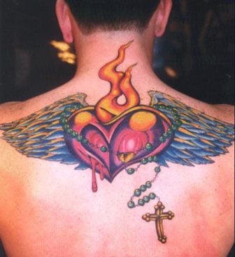 A tattoo of a bleeding heart with flames, wings and a rosary