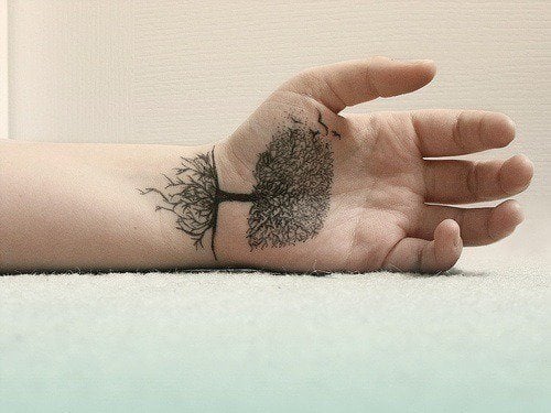 A highly detailed tree tattoo on the palm of this guy's hand uses the line between the wrist and palm as the line of the ground.