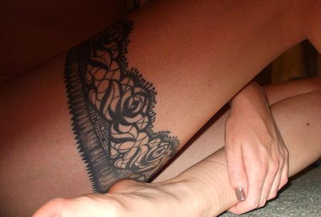 A lacey rose pattern garter belt tattoo gives this girl's thigh a sexy, permanent decoration