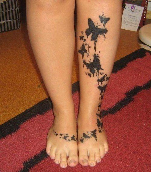 A large tattoo of splatter butterflies that stretches from one foot to the other and up the girl's shin.