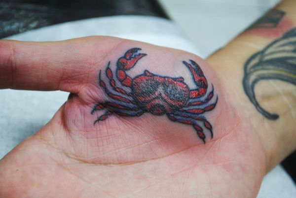 A palm tattoo of a crab, a symbol of the astrological sign Cancer, on the mount of Venus