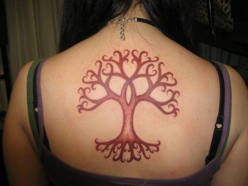 A stylized tree tattoo design in one color ink decorates this girl's uppper back.