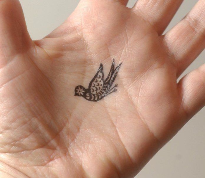 A tiny tattoo of a paisley bird in the palm of the hand.