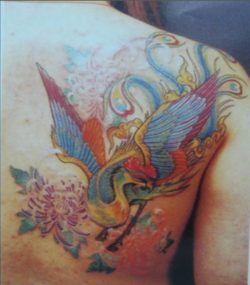 An Asian painting style tattoo design of a peacock bird and flowers decorates this girl's shoulder