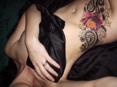 Feminine tattoo of a lotus flower with paisley pattern designs on this girl's hip and tummy.