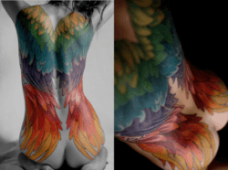 A sexy full back tattoo on a woman that shows angel wings in a rainbow colors