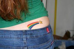 A cute rainbow shooting star tattoo decorates this girl's hip