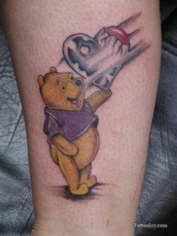 A cute love tattoo that shows Winnie the Pooh bear holding a heart balloon