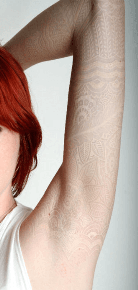 A white lace tattoo on pale skin creates the subtle illusion that this girl has lace beneath her skin