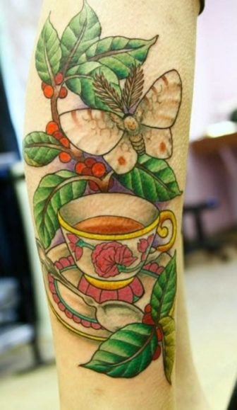 This tattoo design uses a tea cup, a moth and a tree branch to commemorate a deceased loved one