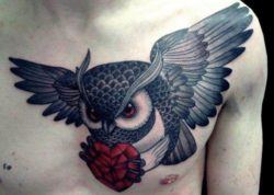 A cool tattoo in red and black of a flying owl carrying a red crystal heart
