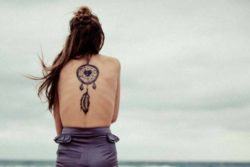 A large dreamcatcher tattoo with a heart at its center and a hanging feather