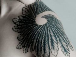 A stunning black and white tattoo of a spiral of feathers
