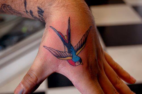A swallow tattoo on the hand that can symbolize travel, loyalty and patriotism