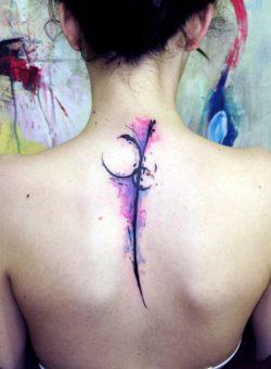 An abstract watercolor tattoo of a feather in feminine pink and purple ink