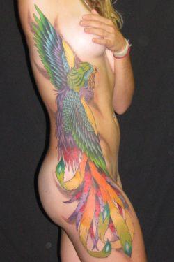 This beautiful phoenix tattoo sports rainbow colors to decorate this girls body from her armpit to her thigh