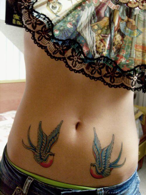 Two swallow tattoos decorate this girls belly with red, blue and white colors