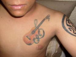 This music tattoo uses the curls of a treble clef to decorate the acoustic guitar tattoo design