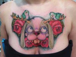 A jackalope, blue birds and roses are the subjects of this Ed Perdomo cartoon style tattoo