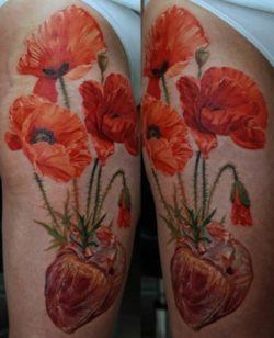 Poppy flowers grow out of a human heart in this photorealistic tattoo by Dmitriy Samohin