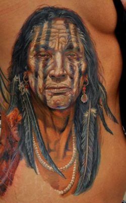 This portrait tattoo of a native American tribal elder uses white tattoo ink to add highlights to the eyes and facial features
