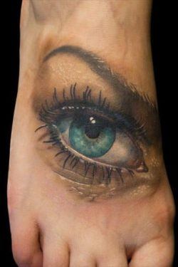A beautiful photo realistic tattoo of a blue eye by Nick Morte placed on the top of the foot