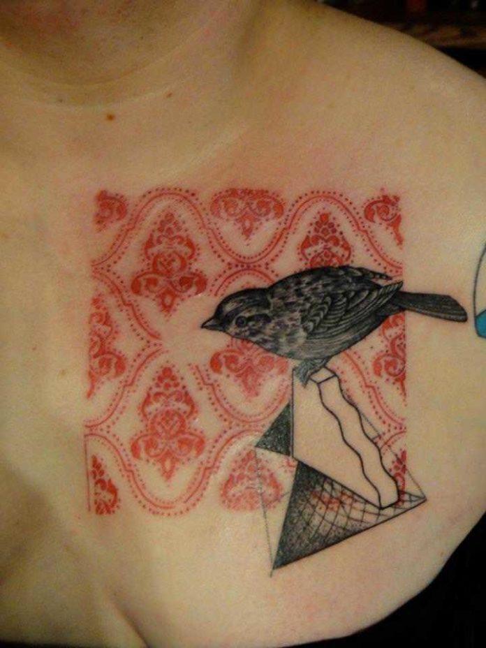 A small bird inspects a paisley pattern in this artistic tattoo by Xoil