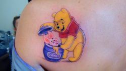 An incredible tattoo of Winnie the Pooh discovering Piglet in a honey jar