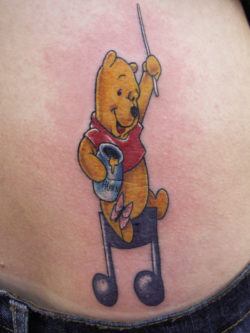 This Winnie the Pooh tattoo shows Pooh Bear directing music while holding his favorite honey pot
