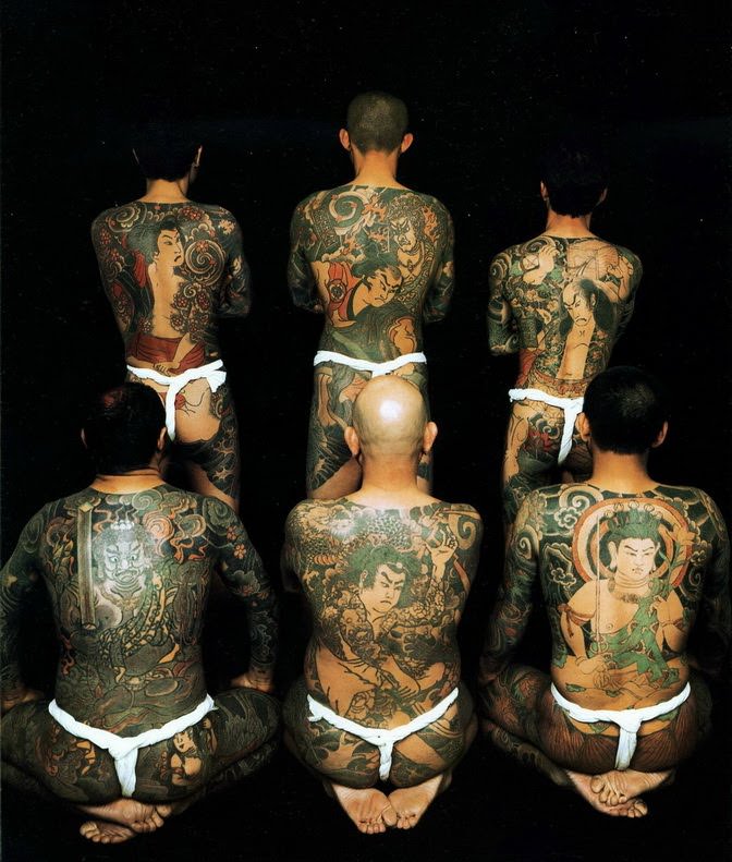 Yakuza gang members pose for a photograph that shows their traditional irezumi tattoo designs