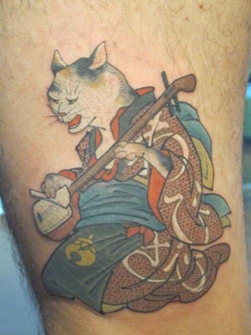 A Japanese cat plays a stringed instrument in this Oriental tattoo by Hide Ichibay