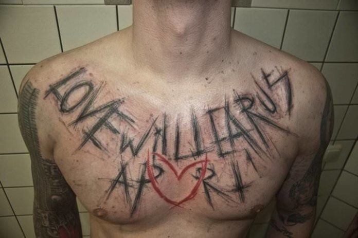 A scratchy text tattoo by Berliner Sven Groenewald that reads Love will Tear us Apart