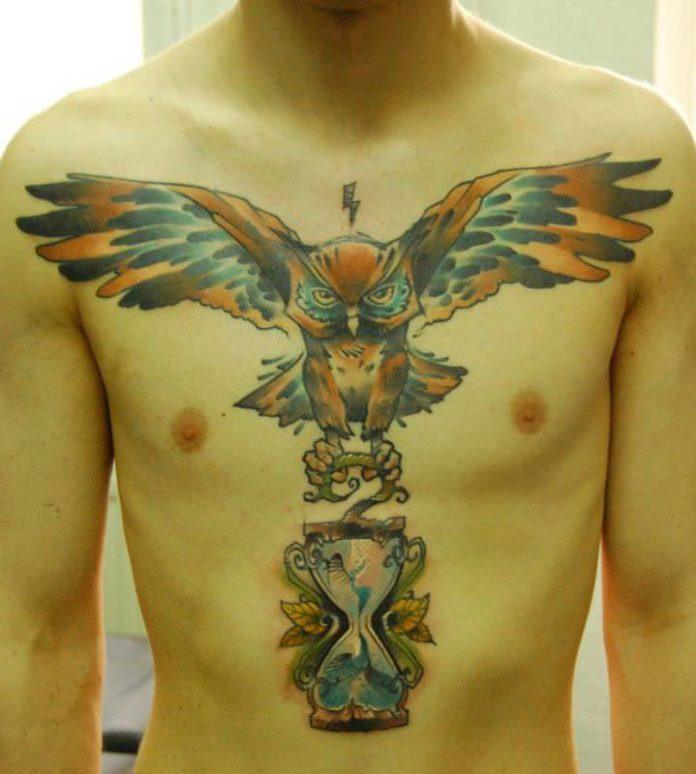 An owl carries an hourglass in this chest piece tattoo by Berlin artist Jukan