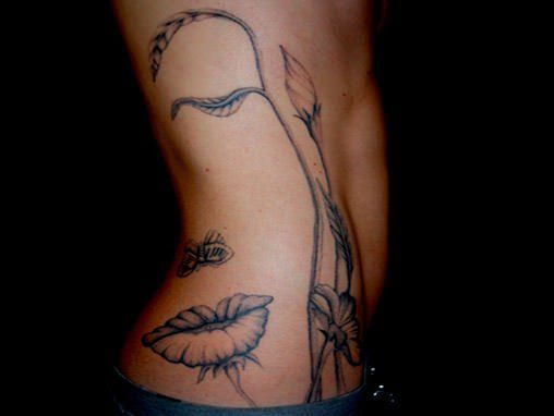 Tattoo of an Octavio Ocampo design that shows either flowers and a butterfly or a womans face