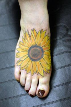The strong silhouette of this sunflower tattoo makes it recognizable from a distance