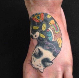 White tattoo ink really makes this tattoo of a cat sleeping stand out from the skin
