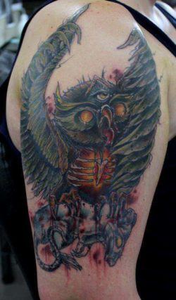 An owl with three eyes clutches a rat in this artistic watercolor tattoo by Australian artist Mel Wink