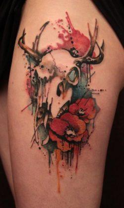 Gene Coffey tattoos symbols of life and death in this artistic watercolor tattoo of an animal skull and poppy flowers