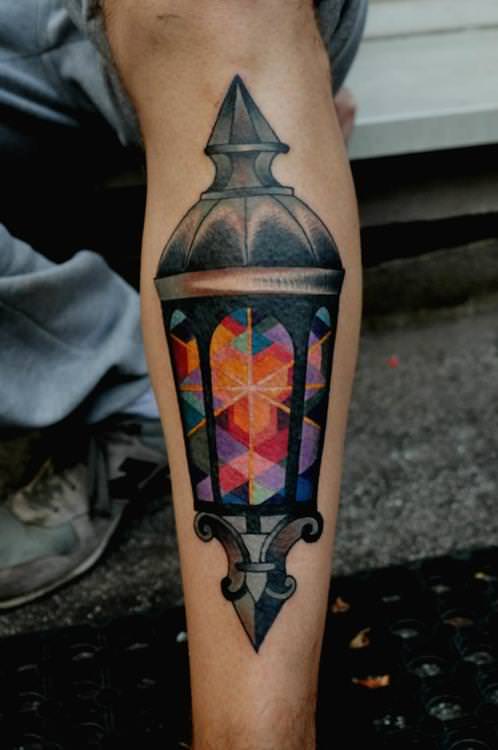Marcin Surowiec tattoos an antique street lamp with cubist colors in this artistic vintage tattoo