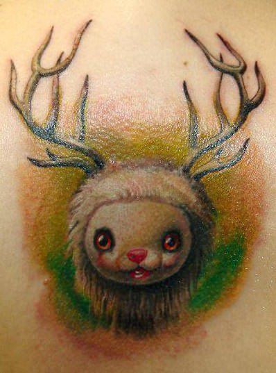 A little lamb with reindeer horns gives a cute smile in this pop surrealist tattoo by Gábor Jelencsik